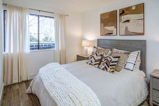 A bedroom with a large bed and two paintings on the wall.