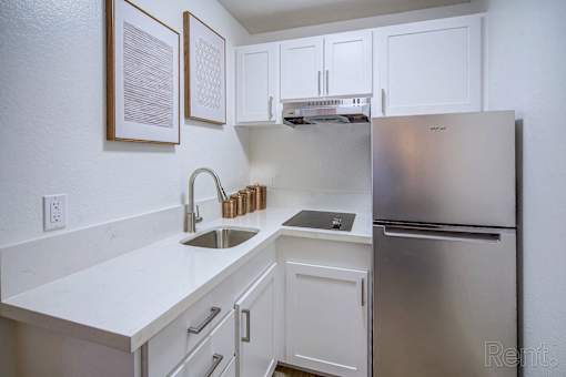 A kitchen with a stainless steel refrigerator and white cabinets.