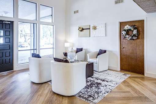 A living room with a black door, a white sofa, and a wreath on the door.