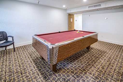 A pool table in a room with a chair and carpeted floor.