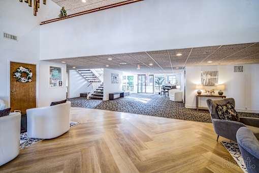 A living room with a wooden floor and a staircase in the background.