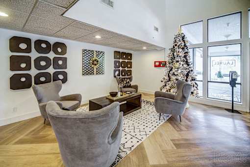 A living room with a Christmas tree and grey chairs.