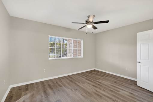 A room with a ceiling fan and a window with blinds.