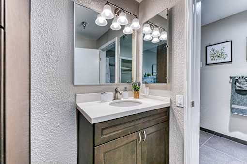 A bathroom with a white sink and a mirror above it.