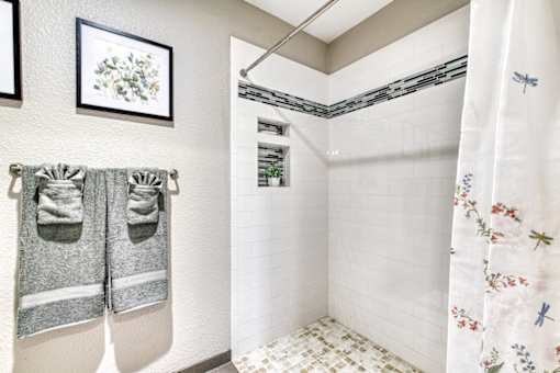A bathroom with a white shower curtain and a white tiled shower wall.