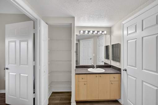 A bathroom with a sink, mirror, and cabinets.
