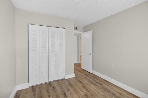 Closet with white doors in a room with wood floors.