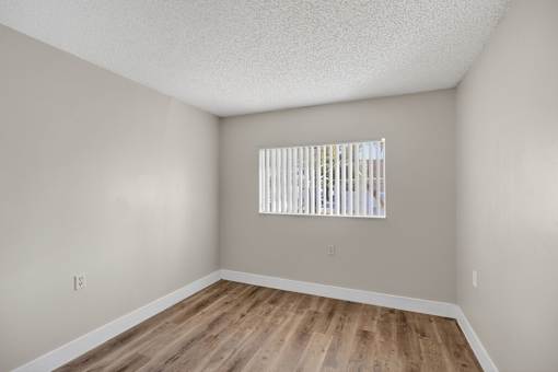 A room with a window and wooden flooring.