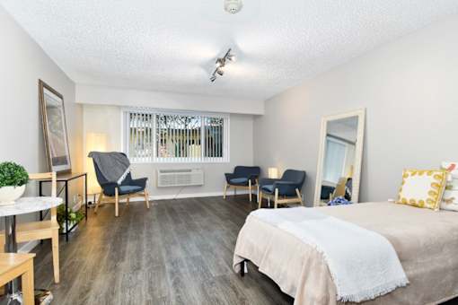 A bedroom with a bed, chair, and a table.