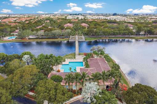 A house with a pool is surrounded by trees and is located near a body of water.