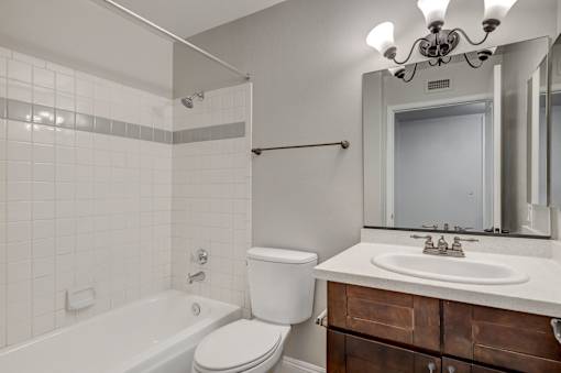 A white toilet sits next to a white bathtub in a bathroom.