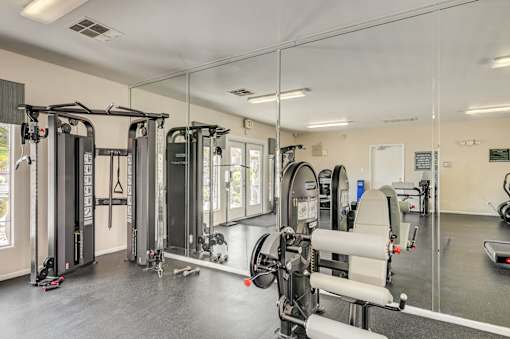 A gym with a variety of equipment including treadmills, weights, and exercise machines.
