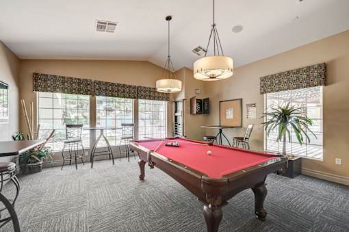 A pool table is in the middle of a room with a carpeted floor.