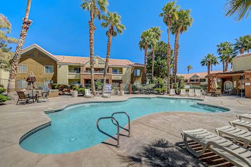 A swimming pool surrounded by palm trees and lounge chairs.