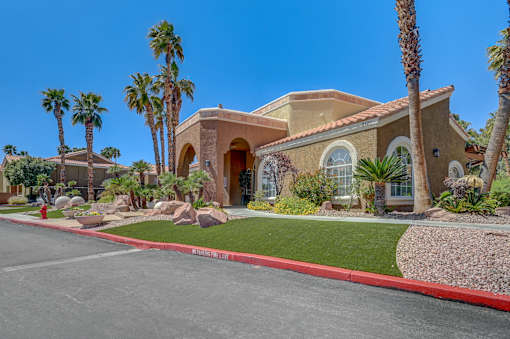A house with a red curb and palm trees in front.