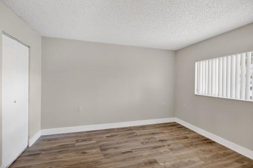 A room with wooden flooring and a window with blinds.