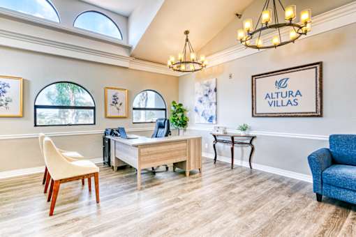 A room with a desk, chairs, and a framed sign that says "Altura Villas".