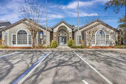 Clubhouse building with arched entryway and parking at The Ivy at Gatehouse Apartments, Orlando, FL