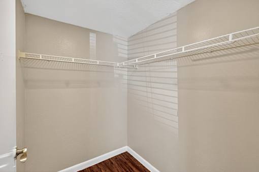 A walk-in closet with a white door and a white shelf.
