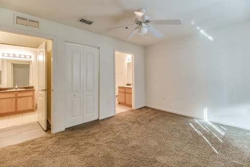 A room with a carpeted floor and a ceiling fan.