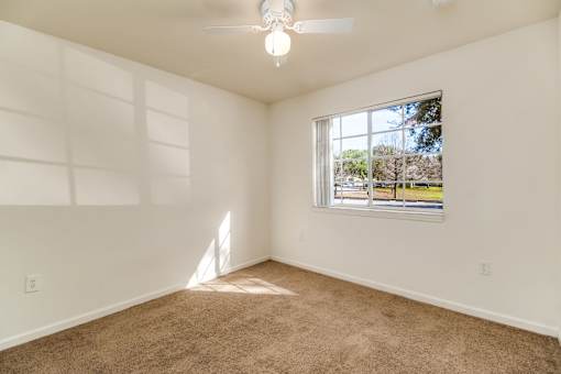 A room with a ceiling fan and a window showing an outdoor view.