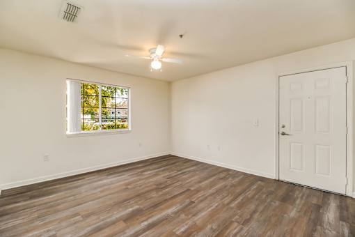 A room with a white door and a window with a view of trees.