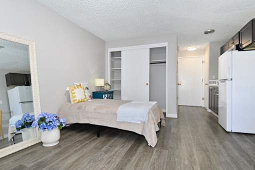 A bedroom with a bed, a mirror, and a vase of flowers.
