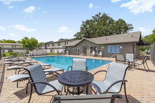 A poolside area with chairs and a table.