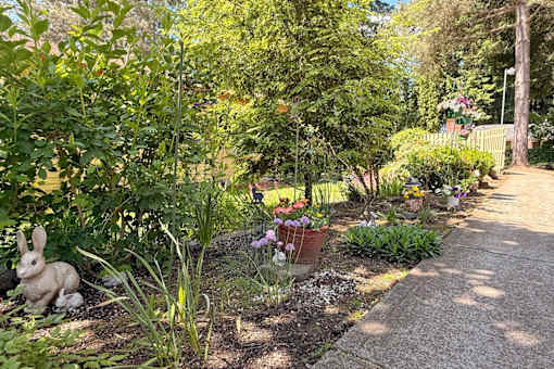 A garden with a statue of a rabbit and a variety of plants.