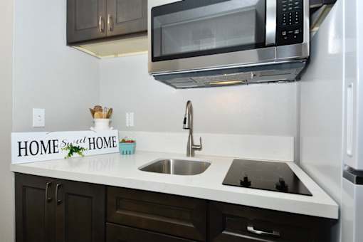 A kitchen with a white countertop and a black microwave above it.