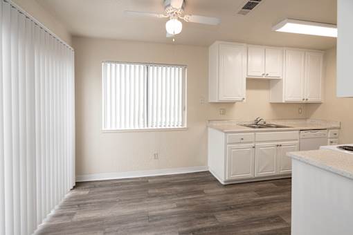 A kitchen with white cabinets and a wooden floor.