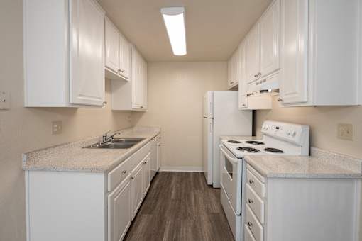 A kitchen with white cabinets and a white stove top oven.