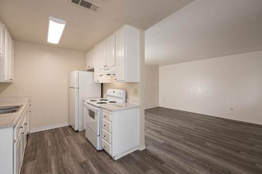 A kitchen with white appliances and wooden floors.