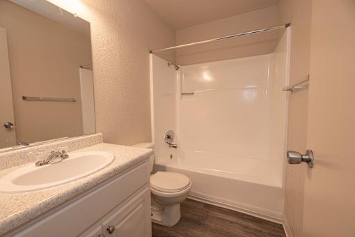 A white bathroom with a sink, toilet, and shower.