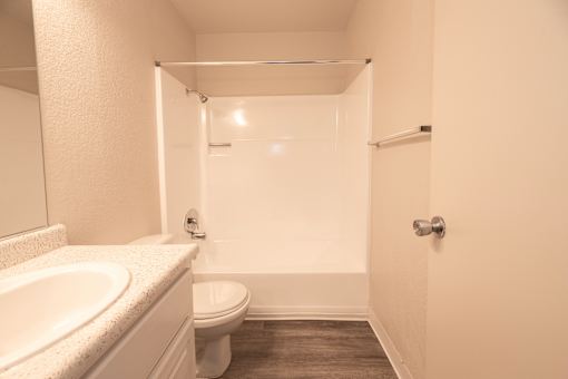 A white bathroom with a toilet, sink, and shower.