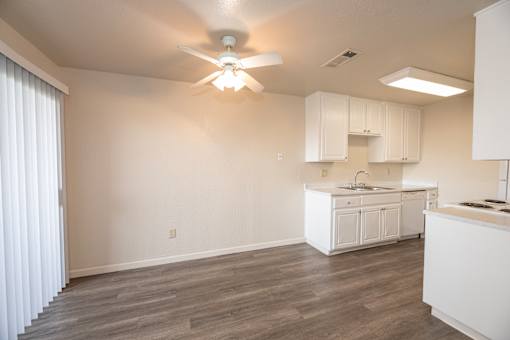 A kitchen with white cabinets and a ceiling fan.