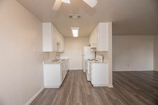 A kitchen with white appliances and wooden floors.