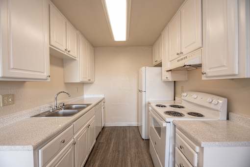 A white kitchen with a sink and stove.