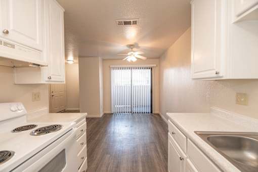 A white kitchen with a stove top oven and a sink.