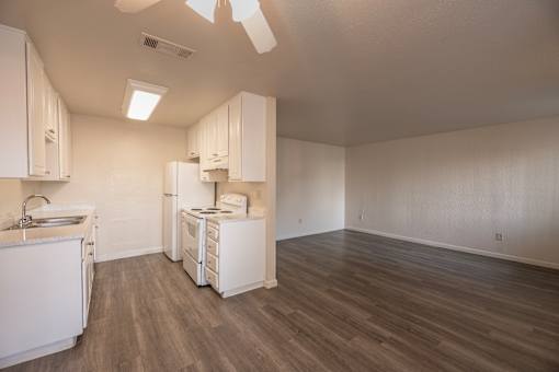 A kitchen with white appliances and wooden floors.