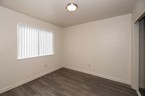 A room with a window and wooden flooring.