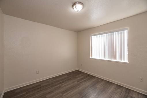 A room with a window and wooden flooring.