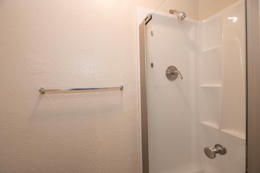 A white door with a silver handle and a silver bar on the wall.