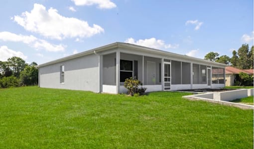 A modern house with a grey exterior and a green lawn in front.