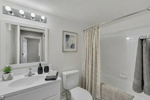 A bathroom with a white toilet, sink, and shower area.