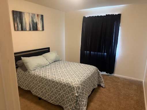 A bedroom with a patterned bedspread and a black headboard.