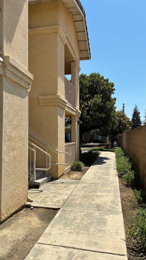 A concrete staircase with a metal railing leads up to a building.