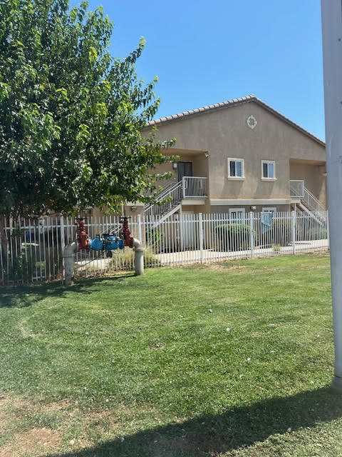 A house with a white fence and a tree in front.
