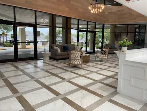 A spacious living room with a checkered floor and a large window overlooking the street.