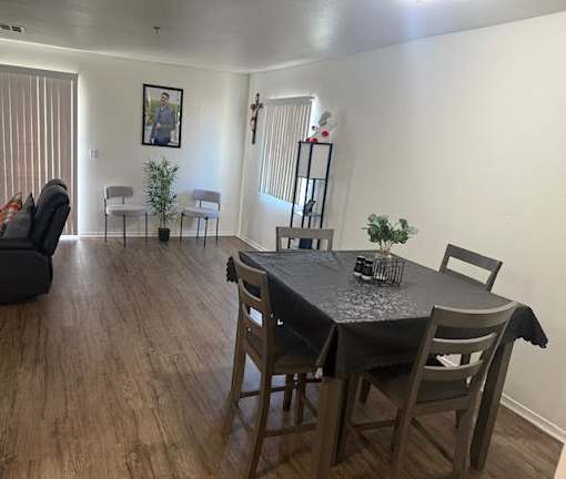 A dining room with a table set for two and a couch.